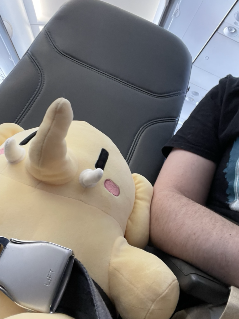 A stuffed Mastodon elephant strapped into an airplane seat. 