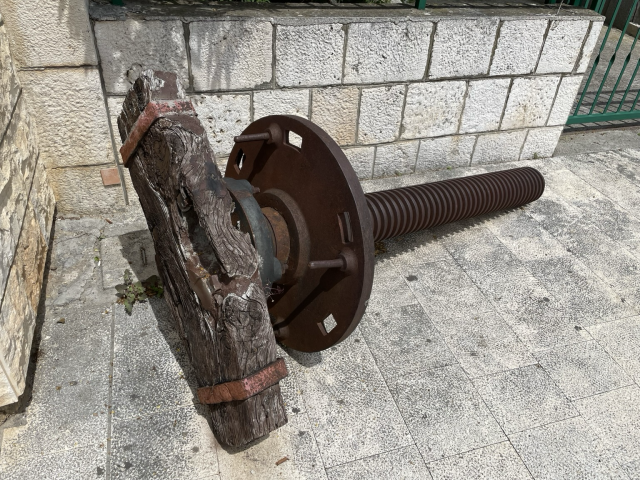 A giant metal bolt with a wooden plank attached at the top. 