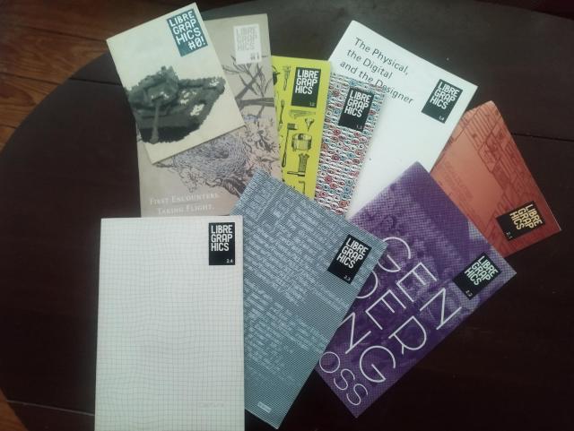 All issues of the libre graphics magazine as print version on a brown table.