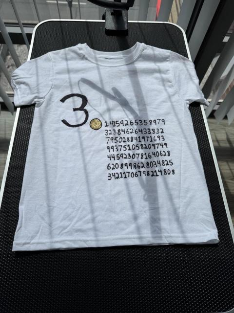 A white tshirt with many digits of pi and I large gold decimal 