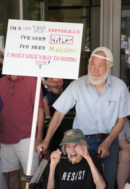A elderly woman sits in a wheelchair. Above her is a sign that reads "I'm a 104 year old Republican. I've seen Hitler. I've seen Mussolini. I don't like what I'm seeing now"
