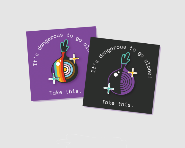 a set of enamel pins in the form a stylized onion. the pins are pinned on a cardboard square with printed text on it reading "It's dangerous to go alone! Take this."