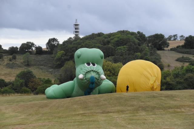 Two partially deflated hot air balloons on a hillside