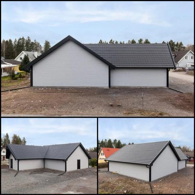 White house with gray roof and black corners and edges. The house has no windows at all.