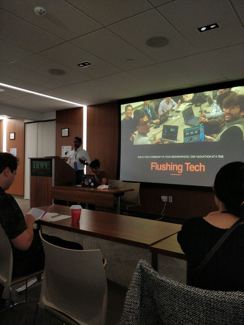 Front of a lecture room with a dude in a nice shirt and the title slide: flushing tech