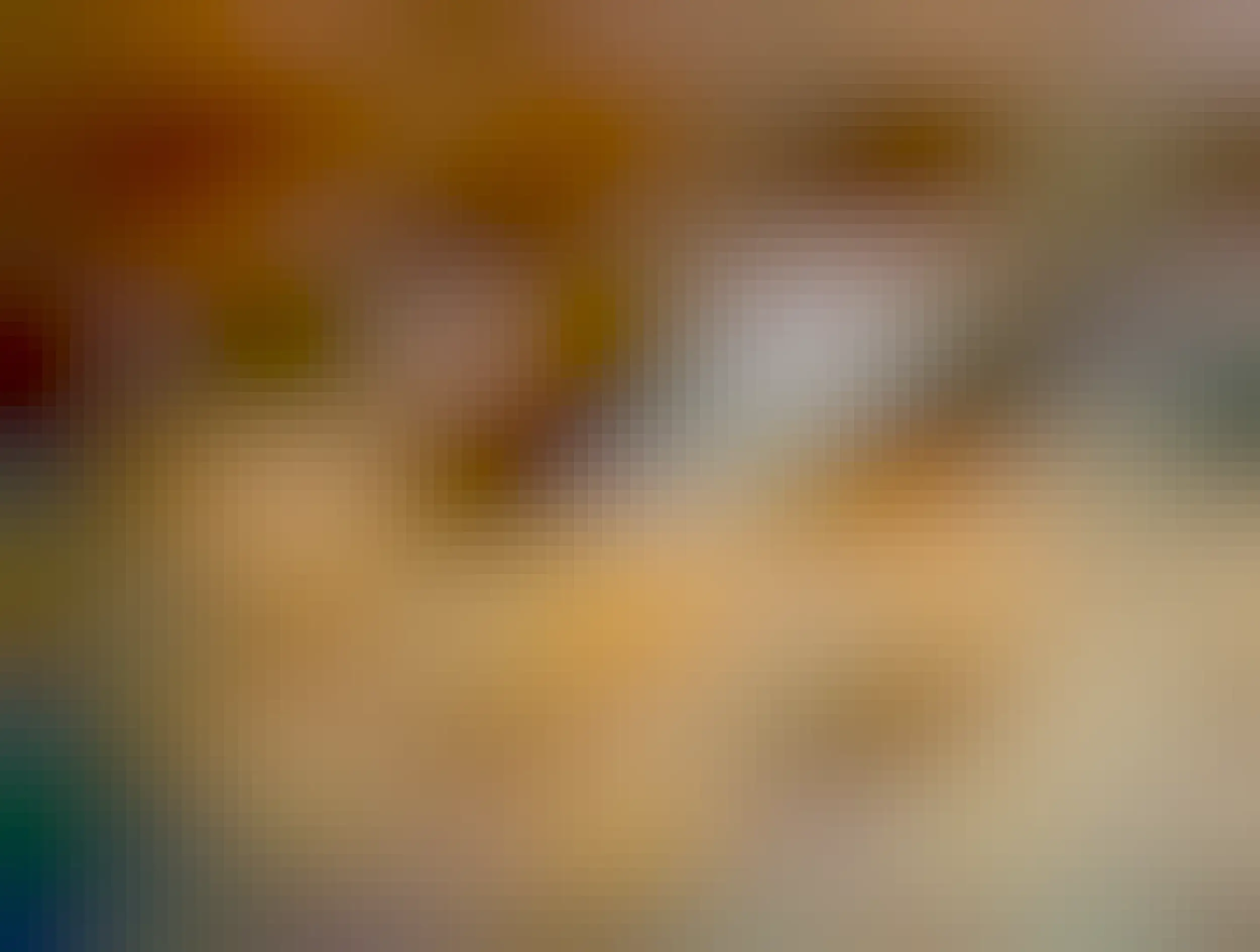 A black and white tuxedo cat sits snugly inside a cardboard box labeled “b.f.f Best Feline Friend, OMG – Oh My Gravy!, Variety Pack – Rainbow A Gogo.” The cat is lounging comfortably with its front paws draped over the edge, looking directly at the camera with bright eyes. The box is placed on a tiled floor in front of a fireplace screen.