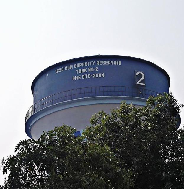 A large blue and white water tower above some trees. It says "1250 CUM CAPACITY RESERVOIR TANK NO-2 PHE DTE-2004" on it. HAHA CUM