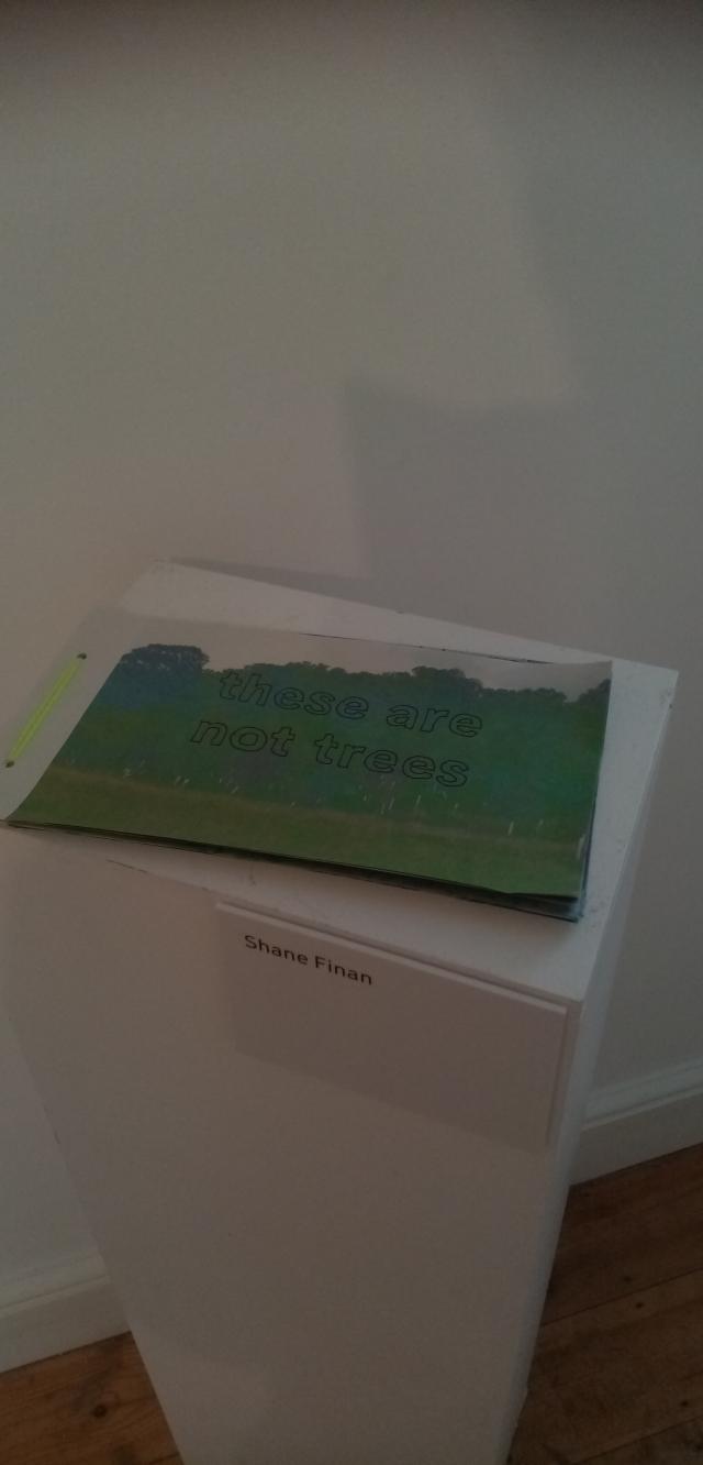 A small handmade book with printed tree pictures and the words 'these are not trees' hand-written on the front