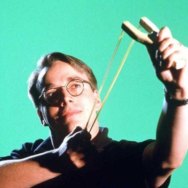 This is a picture of Linus Torvalds with a wooden sling against a light green background.