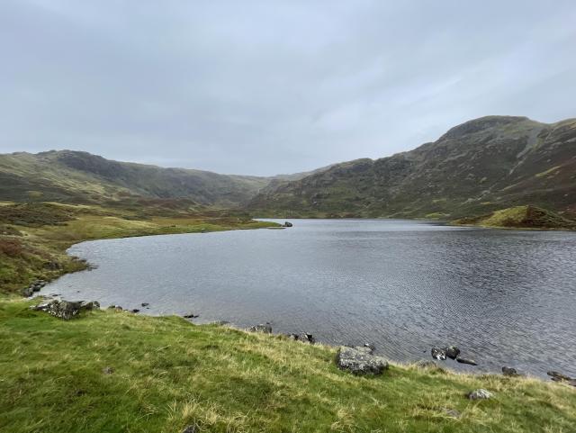 A body of water surrounded by mountains and grass. It is the Easedale tarn. 