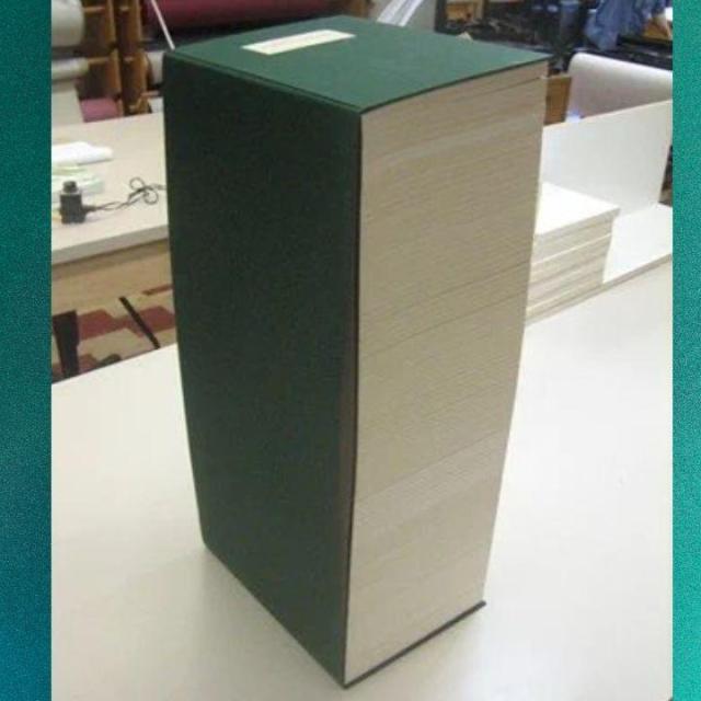 There is a tall dark green covered book sitting on a table.