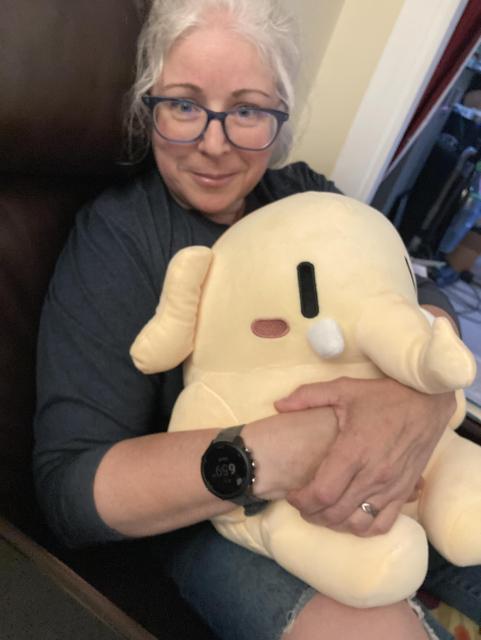 A lady holding a squishy yellow mastodon plush toy 