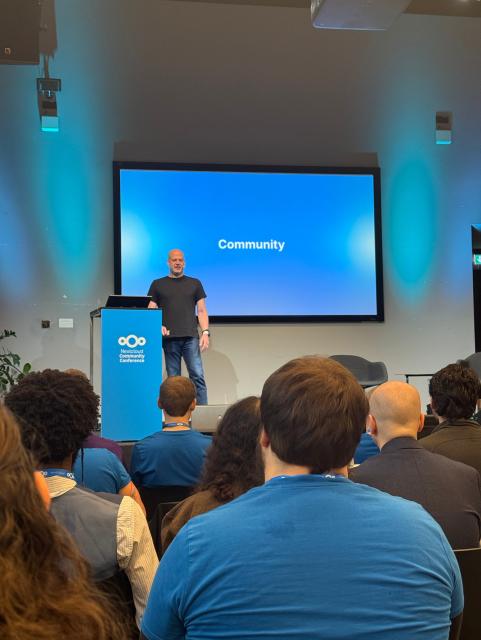 Frank Karlitschek steht auf der Bühne der Nextcloud Community Conference vor einem Bildschirm mit der Aufschrift „Community“. Vor ihm sitzt das Publikum, viele tragen blaue Nextcloud-T-Shirts.