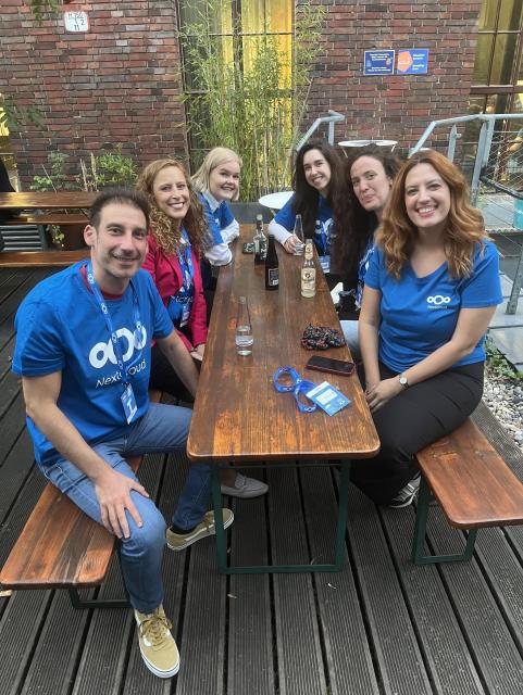 Group picture of six people of the Nextcloud team. They are sitting on a picnic bench outside of the venue, smiling at the camera.