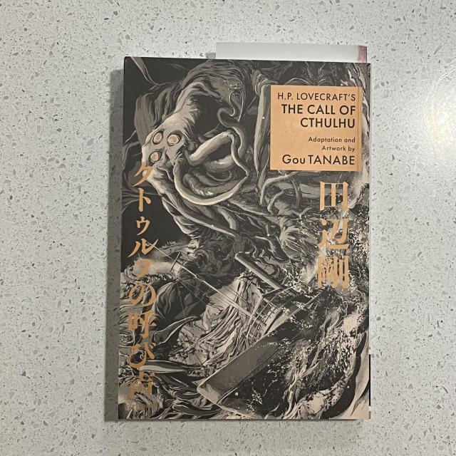 Cover of the manga The Call of Cthulhu featuring a black and white illustration with a large alien monster attacking a boat. Japanese script lines the edges in a metallic rose gold ink. 