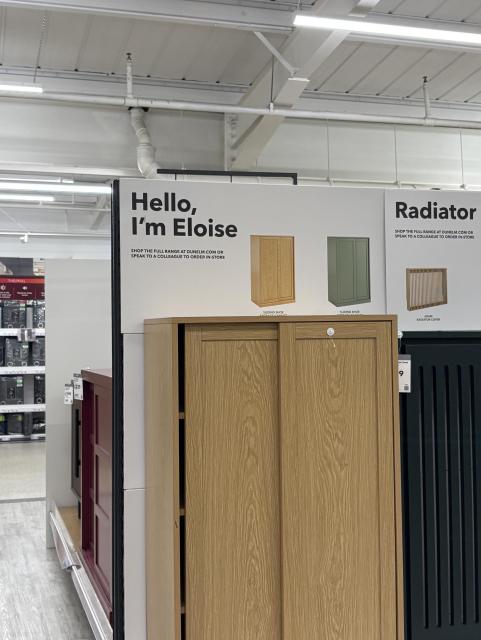 A cupboard in a large furnishings store with a sign behind it that reads in “Hello, I’m Eloise”