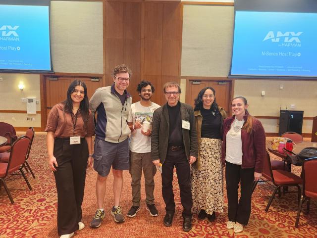 Me and my lab standing with Vincent for a photo (6 people total). Podium and projector in the back.
