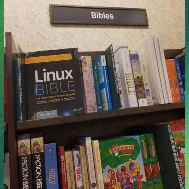 There is a shelf filled with books, one of the books in the "Bibles" section is the "Linux Bible".