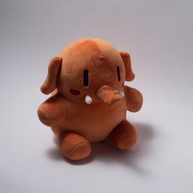 An apricot colored stuffed Mastodon toy sitting comfortably.