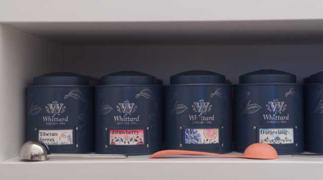 4 Teal coloured stout tea caddies with labels that read: Tibetan Secret, Strawberry, Blue Lady, and Darjeeling. 