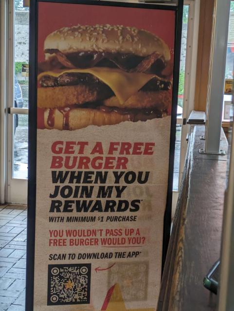 A sign showing a giant burger with text below: "GET A FREE BURGER WHEN YOU JOIN MY REWARDS" and then reward details.