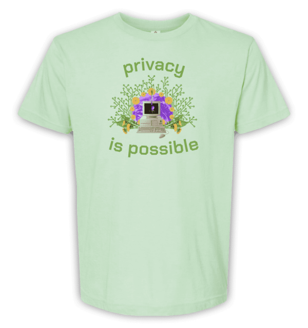 Mint green t-shirt with vintage computer over a purple earth surrounded by daisies and onion roots. Text says privacy is possible.