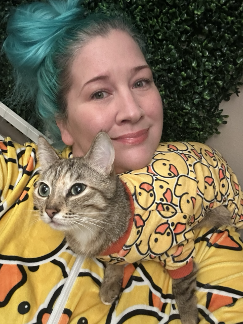 A cat lady and her cat wearing matching duck onesie pajamas 