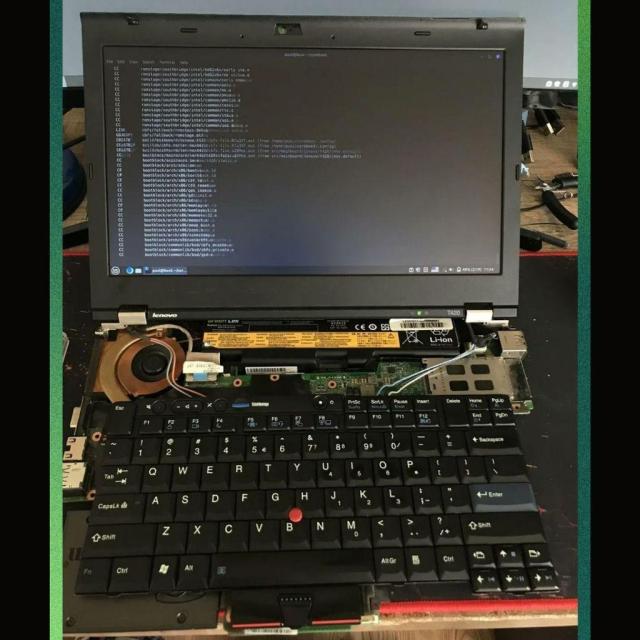 There is a disassembled laptop here with its inner and outer bits visible. We can see the monitor, the keyboard, the motherboard, the cooling fan, the battery, some thin wires, and a few USB ports in this picture.