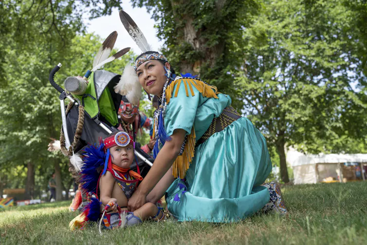 T'ata Begay, of the Choctaw/Taos Pueblo Nations in Oklahoma, gets her son, Okhish Homma Begay, 2, who is of the Navajo and Chocktaw/Taos Pueblo Nations, ready for a performance on the National Mall in Washington, D.C., on June 26, 2024. AP Photo/Jacquelyn Martin 