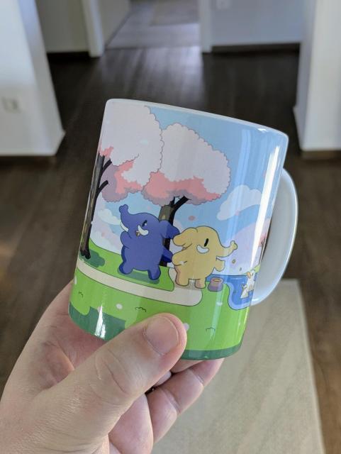 A hand holding the Cherry Blossom Mastodon mug