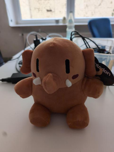 a dark orange mastodon plushie sitting on a white table