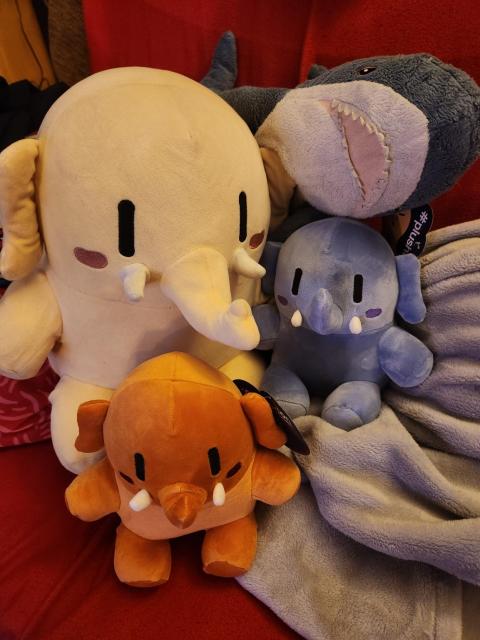 Me hanging out with 3 plushtodons on a couch. One of them is coloured Federation Beige, one Activity Peach and one Interoperability Blue.