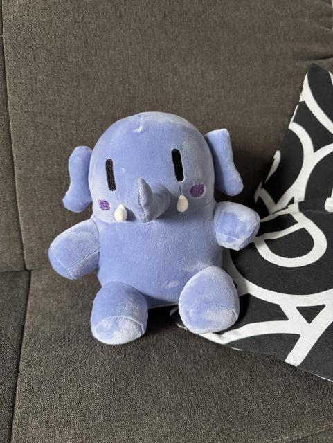 Ein blaues Mastodon-Plüschtier sitzt auf einem Sofa.