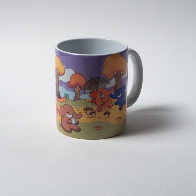 A ceramic mug with a colorful print on it, featuring a blue and a peach colored Mastodon walking under auburn trees, surrounded by mushrooms. One of them is holding an umbrella. Another Mastodon is sitting with a mug of hot beverage.