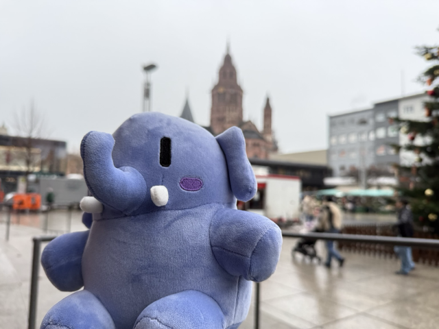 Ein blaues Plüsch-Rüsseltier im Vordergrund, verschwommen dahinter der Mainzer Dom sowie einige Marktstände und am Rand noch ein Teil eines Weihnachtsbaums.