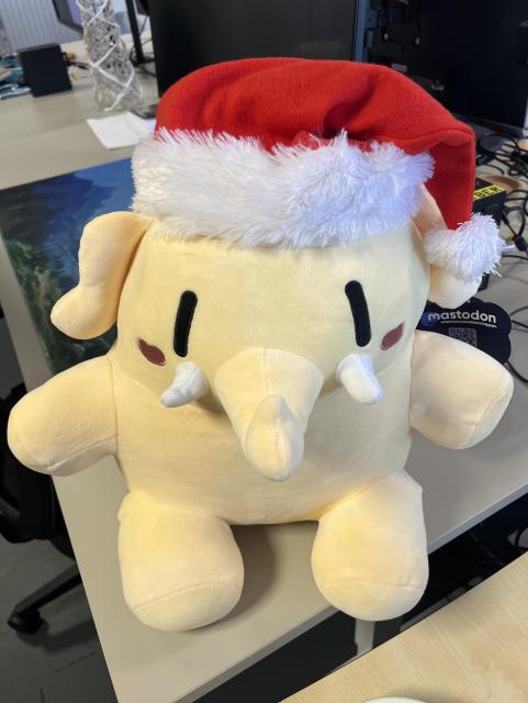 A large mastodon plushie with a Christmas hat
