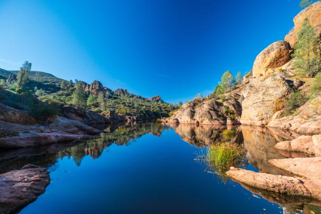 A large body of water reflects blue skies above, and orange rocks to either side. [Fuji X-T5 / Fuji 10-24 WR]