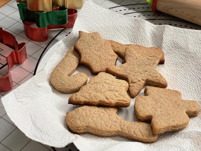 Gingerbread cookies in the shapes of birds, stars, pine trees, candy canes, angels and more cooling down on a plate. 