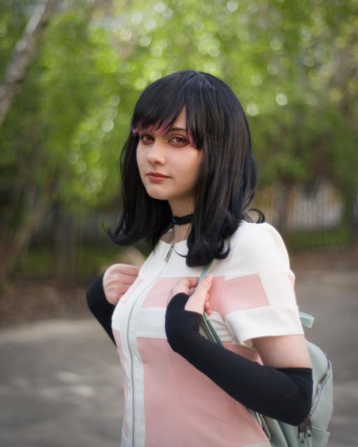 The picture shows a person dressed in a costume that appears to be inspired by an anime or manga character. The individual is wearing a long, dark wig that falls just past the shoulders. The outfit includes a white and pink jacket with a zipper and black long-sleeve gloves. Also there is a light-gray backpack behind her back.
The background features a blurred natural setting with greenery and trees, suggesting an outdoor environment. The overall style and details of the costume and accessories indicate a cosplay or character portrayal.