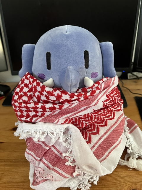 A blue Mastodon Elephant Plushie, wrapped in a Kuffiyeh