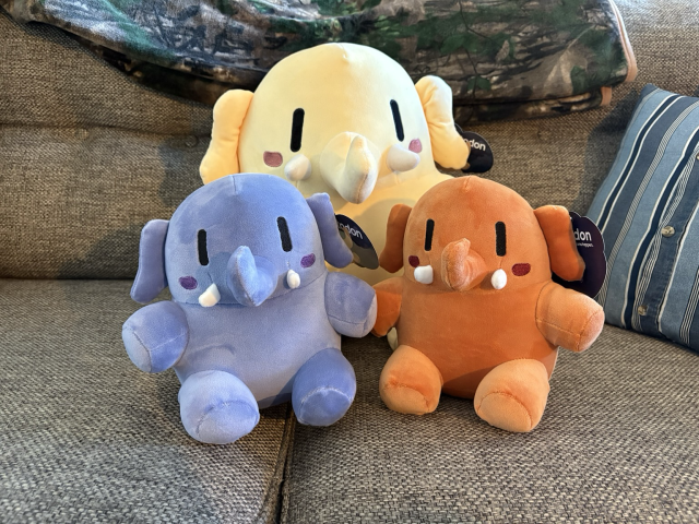 All three plushtodon plushies on a tan couch.