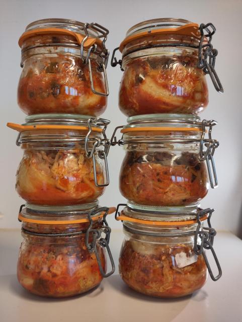 Two towers of three small pots of bright red chunky kimchi