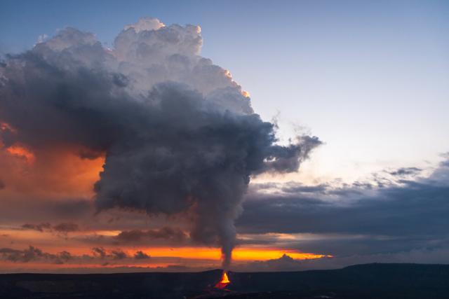 Viewed from far away, a volcano erupts with its plume reaching high into the evening sky. [Fuji X-T5 / Tamron 18-300]