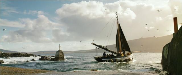 a sailboat going out to sea from port on its own power, with a headsail furled.
Birds are flying around the boat, it is a nice, sunny day.