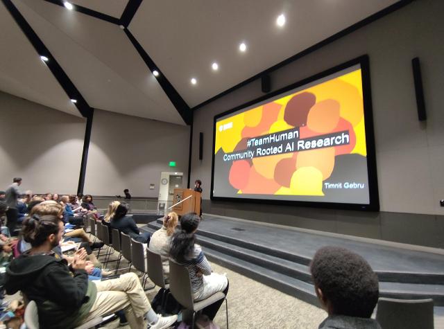 Timnit Gebru at the podium at the start of a talk