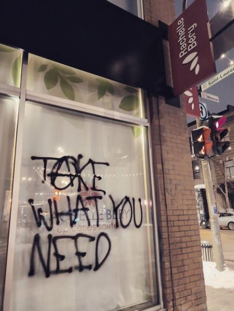 Graffiti "Take what you need" in black paint on the window of a Rachelle Bery grocery store