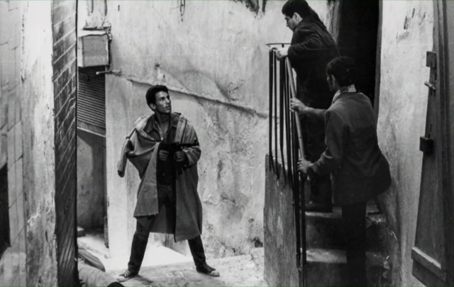 Ali in the streets with a machine gun, looking for law breakers.