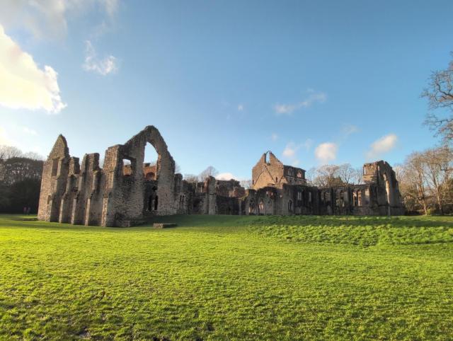 Photo of a ruined 13th century abbey. 

The top of the photo shows clear blue skies, with vibrant green grass below. In the middle, a jumble of ruins.