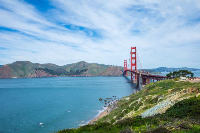 An orange bridge spans a gap between two land masses. [Ricoh GR III]