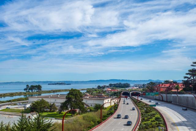 A freeway stretches back toward an island, with blue skies overhead. [Ricoh GR III]